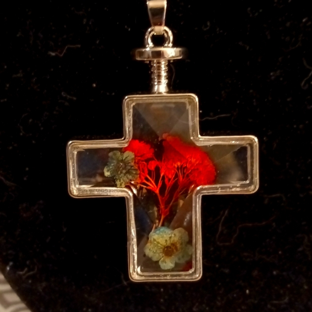 Glass 3D cross necklace with dried flowers inside.